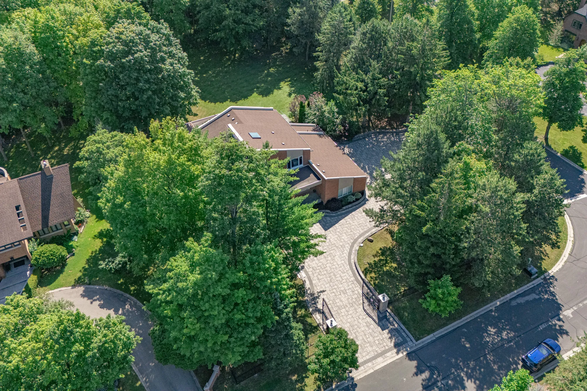 Looking down on the corner: the street curving around the lot, the gate on the curve, a paved drive through the trees to the house at the top