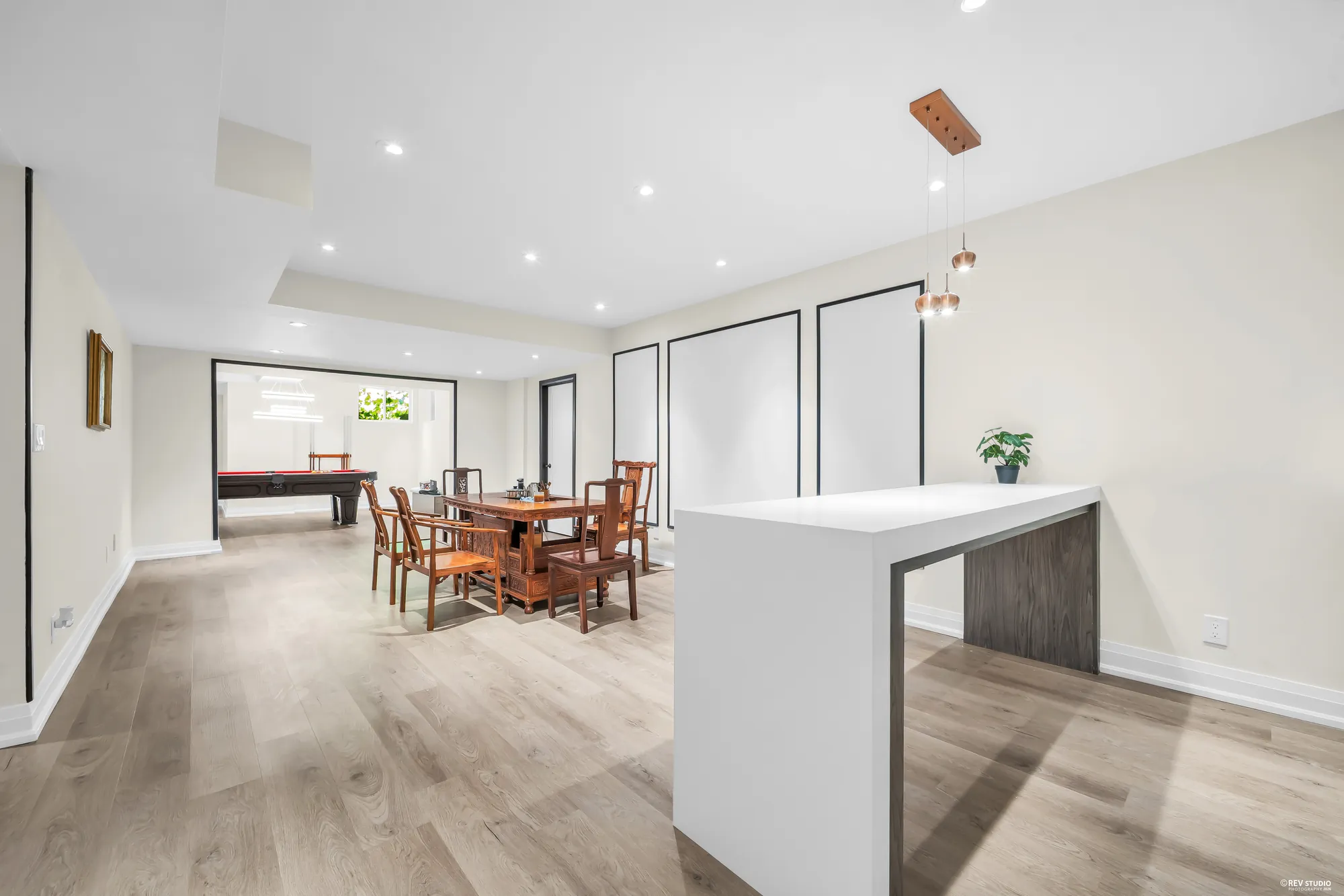 From the wet bar&rsquo;s island toward the dining table, the pool table in the room beyond