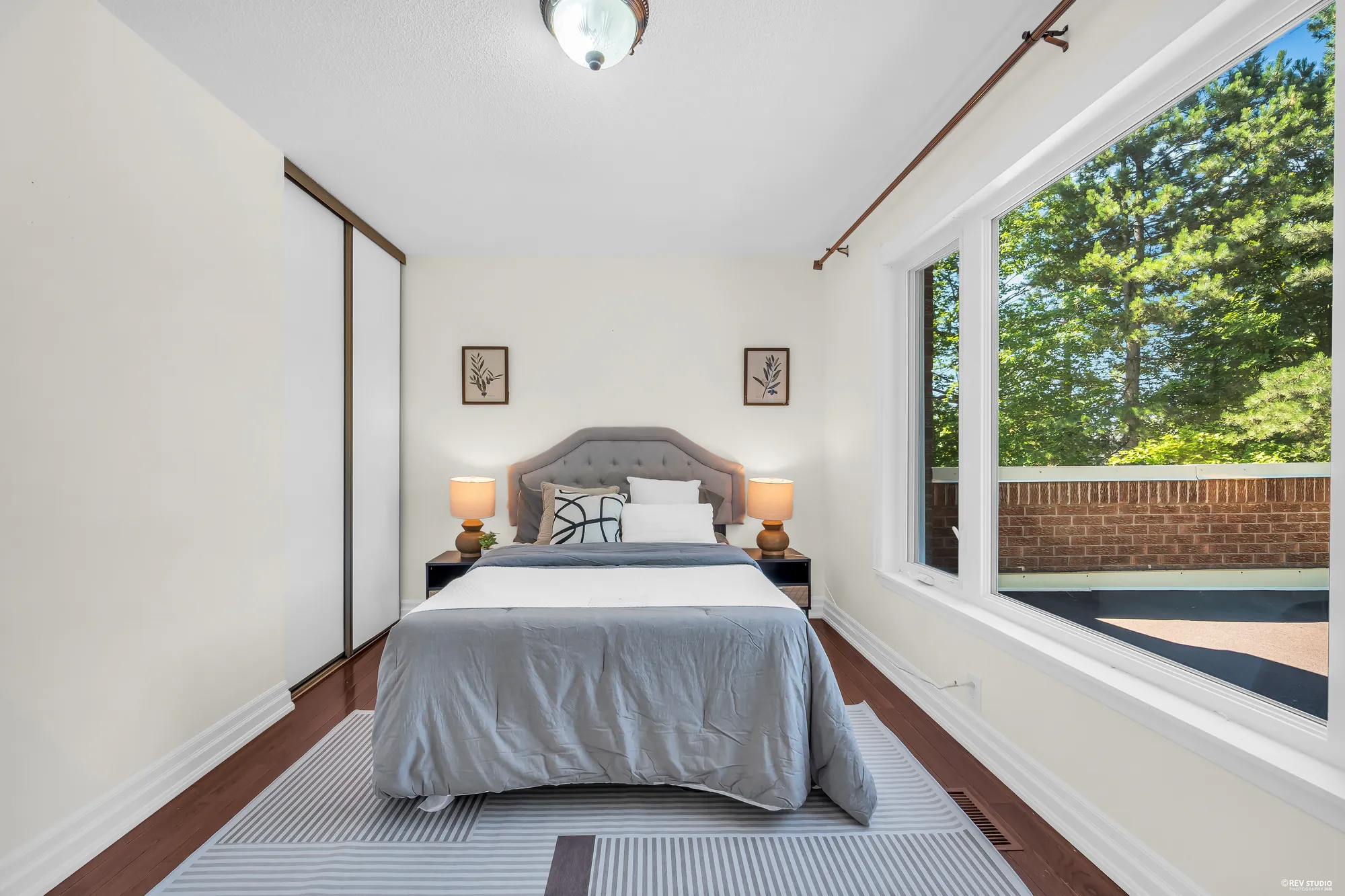 The same bedroom from the door: a sliding closet, the bed at the far wall, the wide window at the right