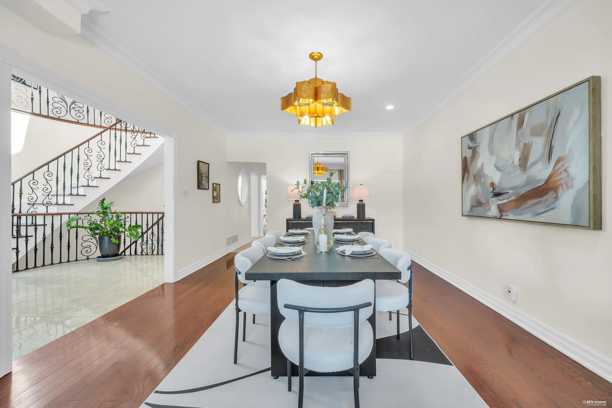 The dining table from the window end, the curved stair and the foyer through the opening at the left