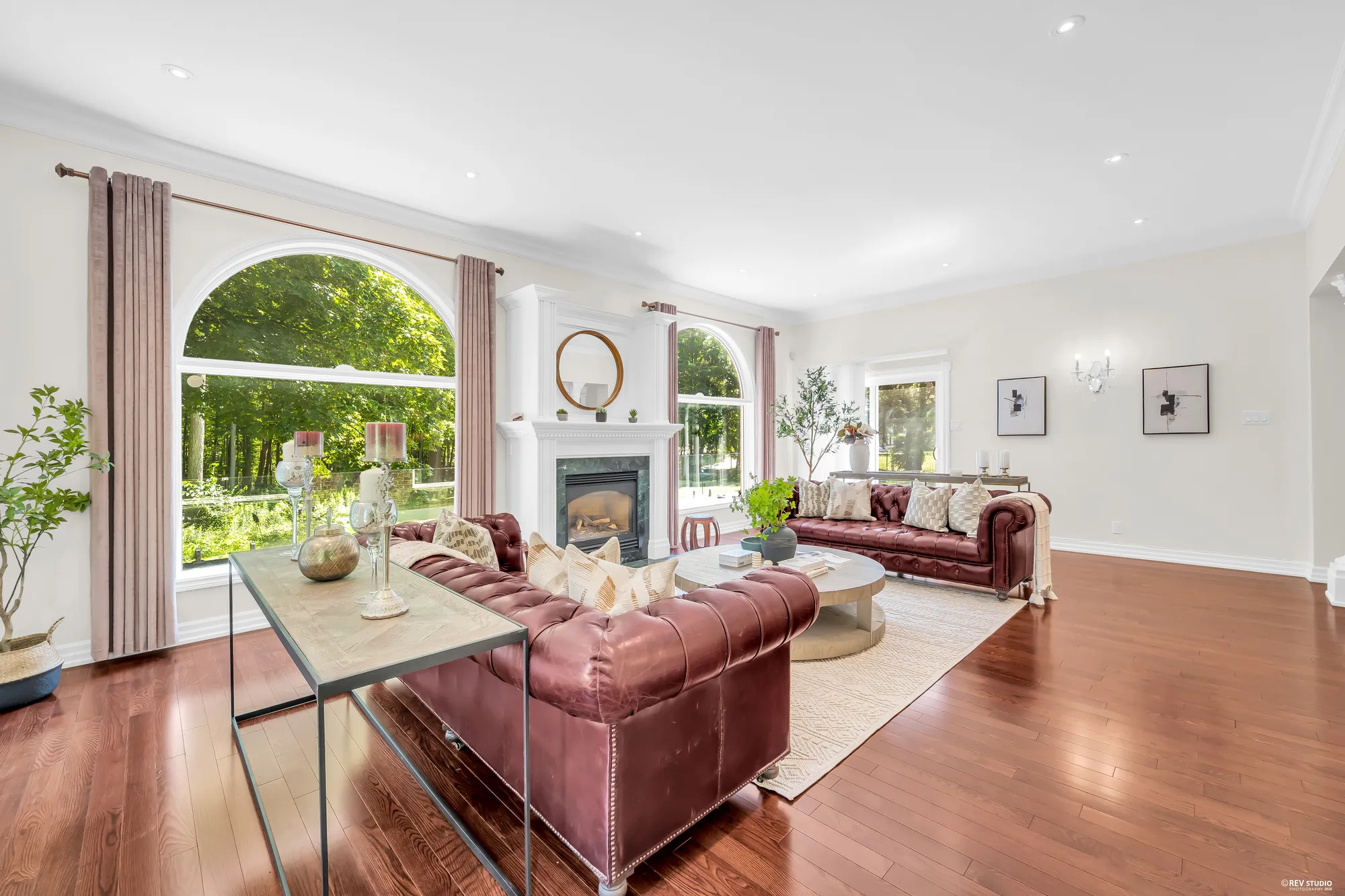 Toward the fireplace past a console table: the arched windows, wall sconces and framed prints