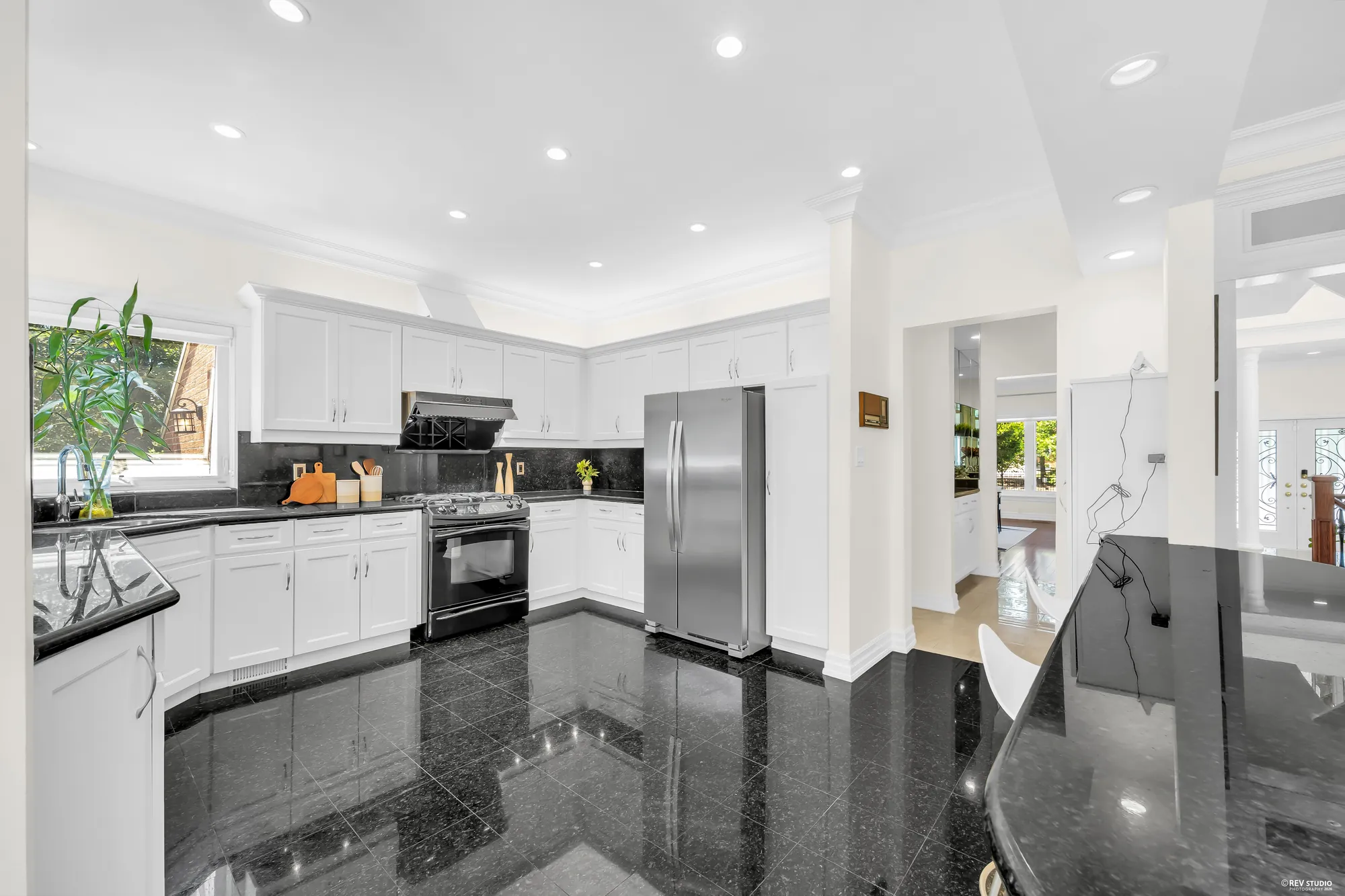 The kitchen across the curved black granite breakfast bar in the foreground