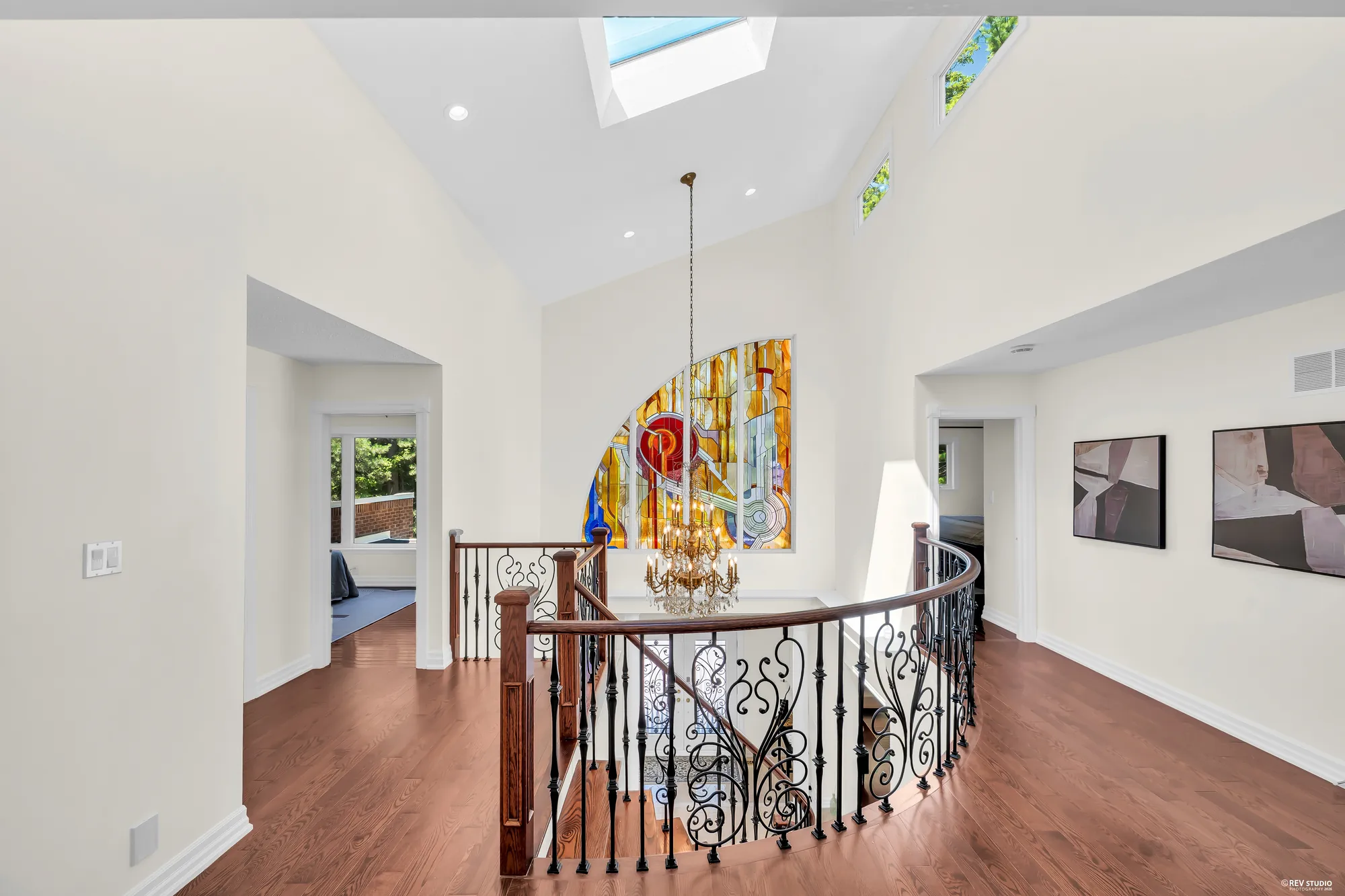 The landing under a skylight and a vaulted ceiling, the stained-glass window over the stairwell, doors to the bedrooms