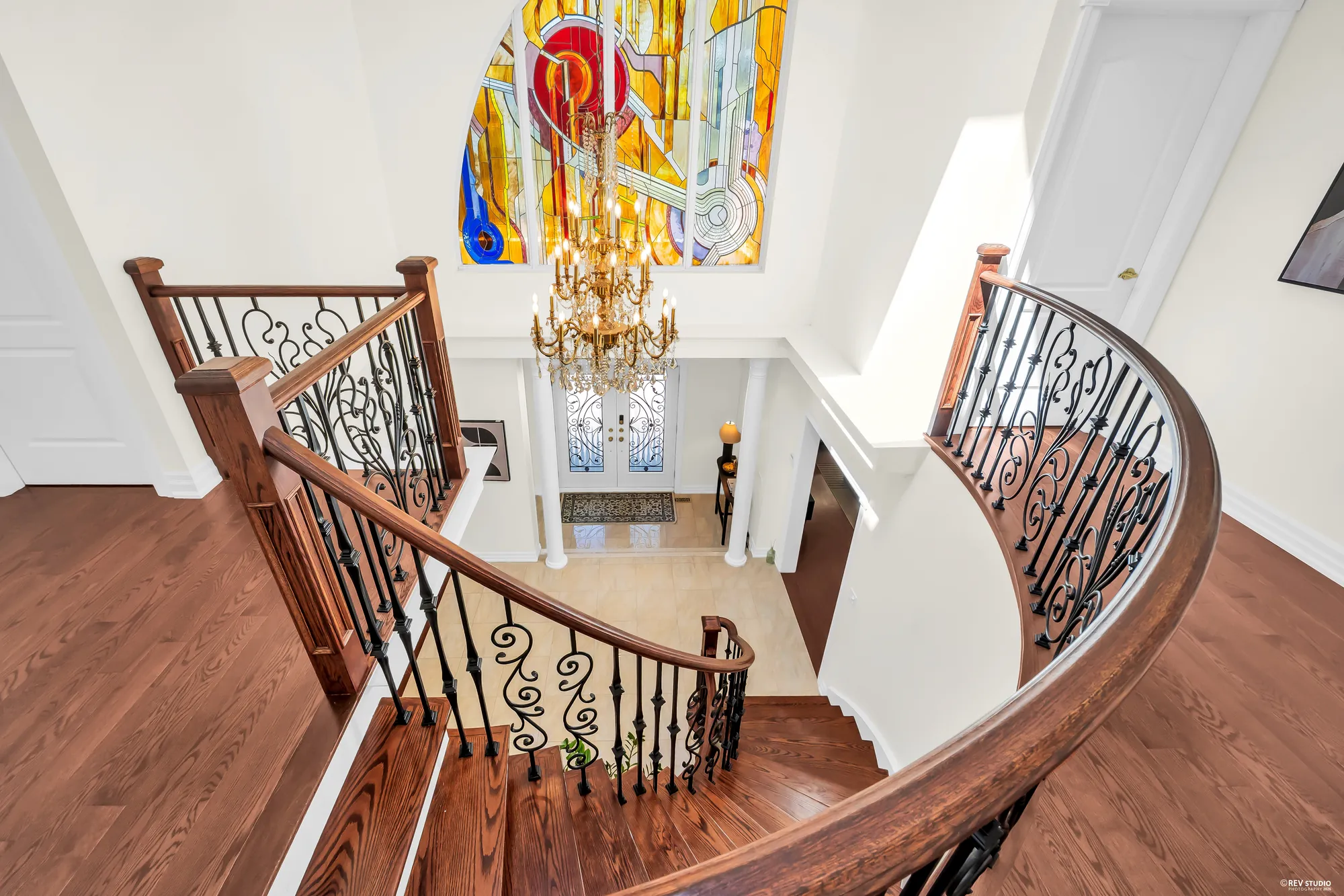The curved stair from above, the chandelier and the stained glass, the foyer floor below