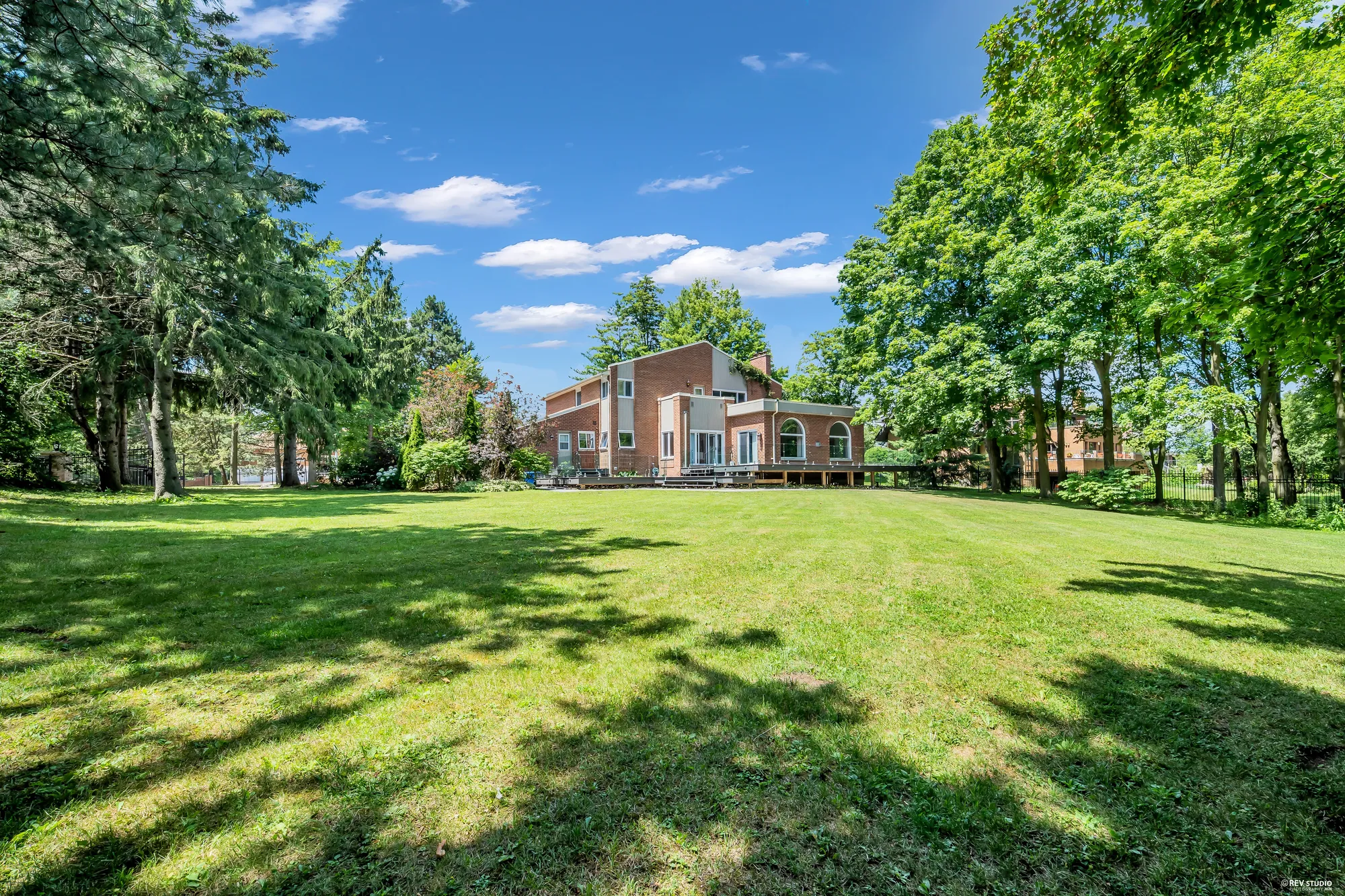 The lawn from the far end of the lot, the house in the distance behind the trees
