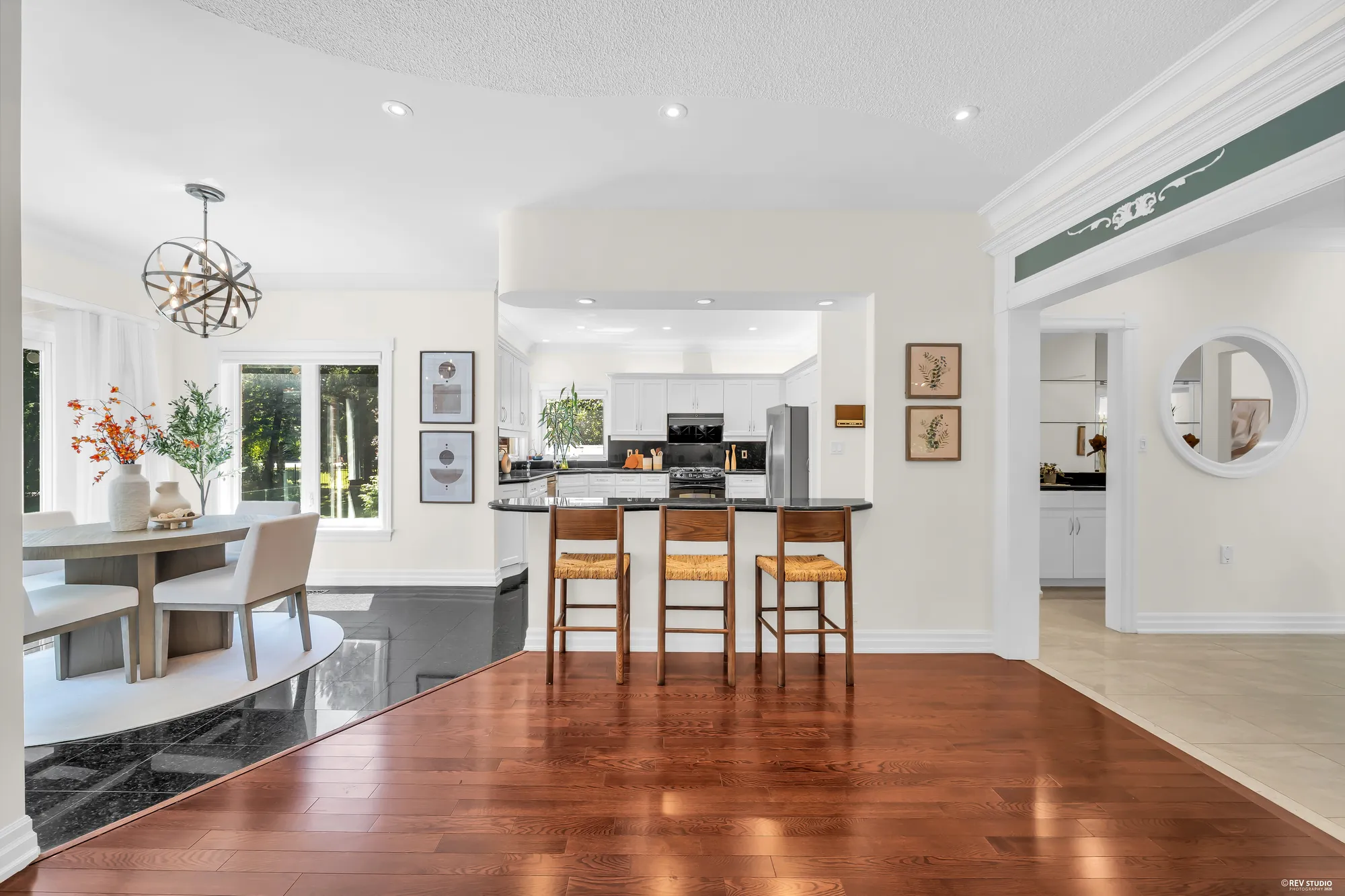 The breakfast nook and the kitchen beyond its bar with three stools, seen from the dining area