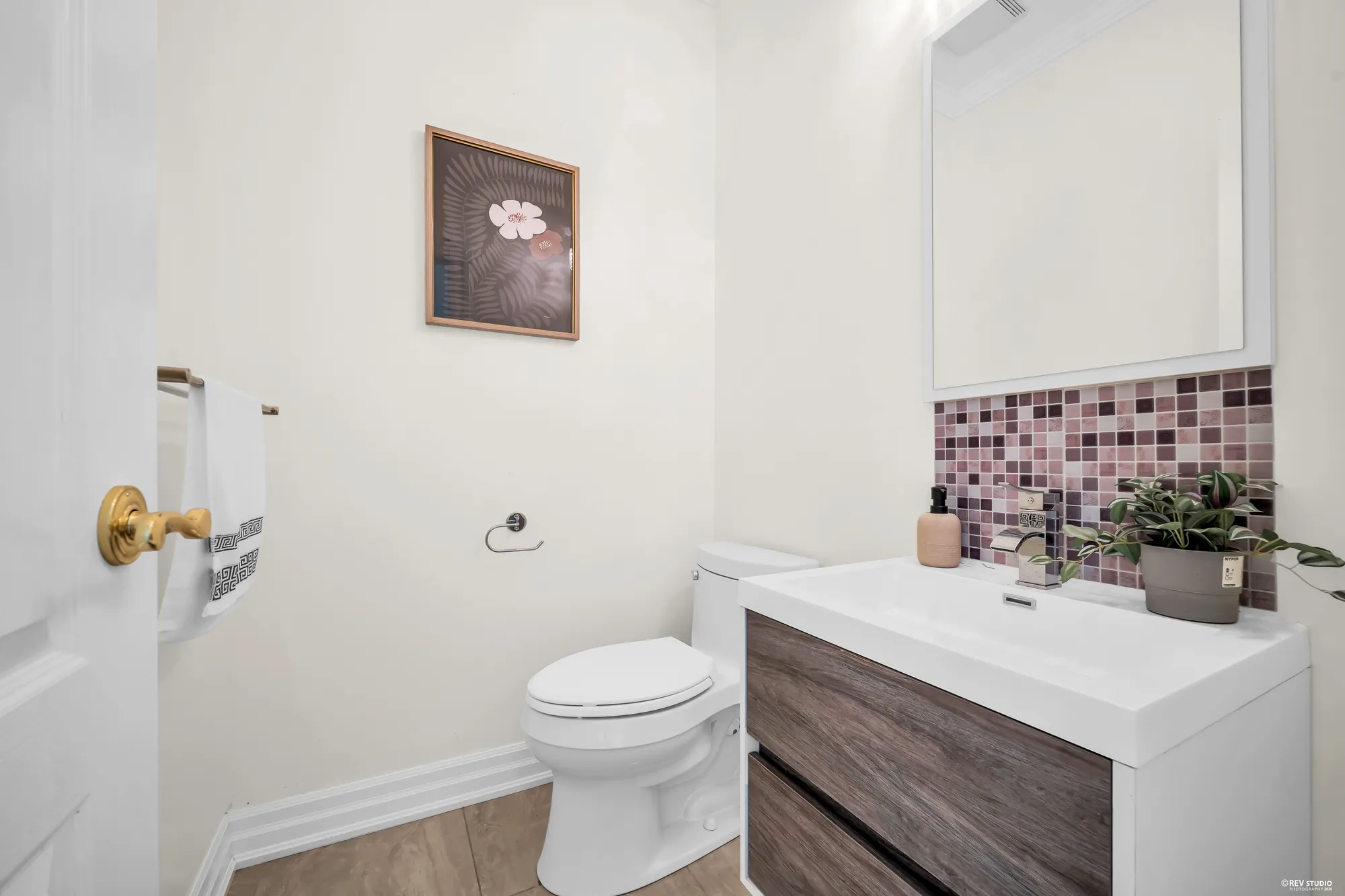 The powder room: a toilet, a floating vanity in dark wood with a white top, a backsplash of plum mosaic tile